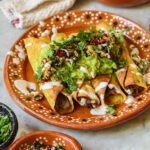 mexican black bean flautas on a plate with guacamole.