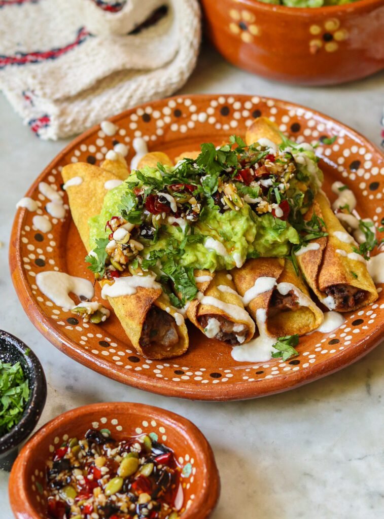 mexican black bean flautas on a plate with guacamole.