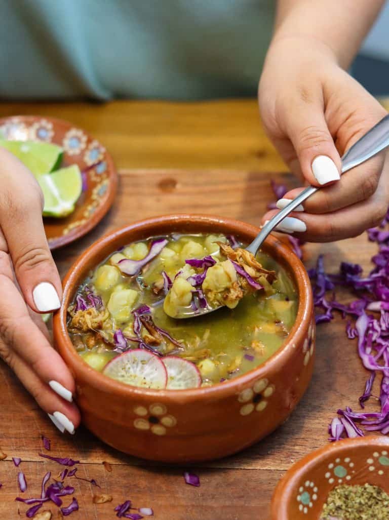 vegan pozole verde in a bowl with toppings.