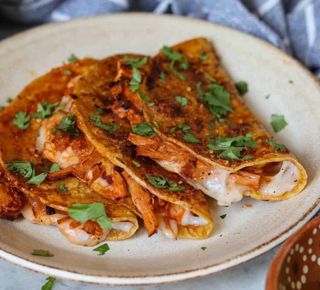 vegan birria tacos on a plate with cilantro.