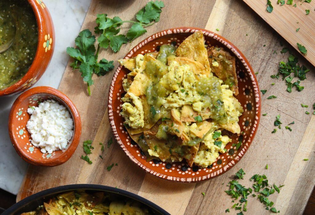 vegan chilaquiles in a mexican plate with cheese and avocado.