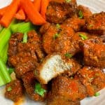 buffalo tofu wings on a plate with celery and carrots.