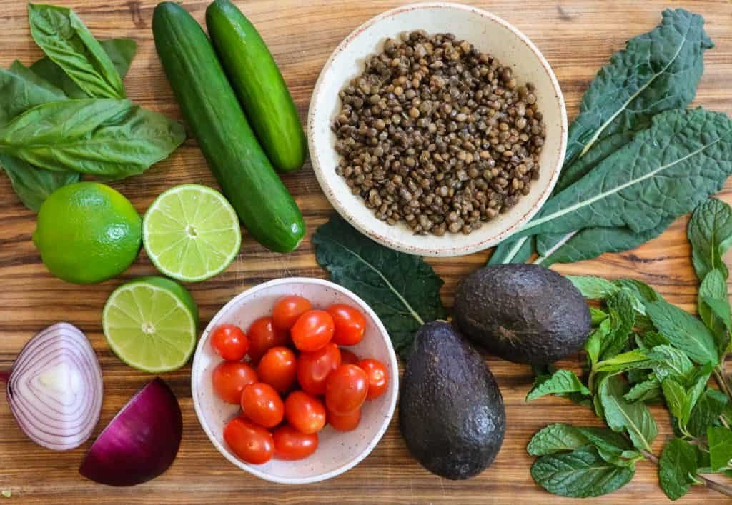 lentil kale salad ingredients on a wooden cutting board.