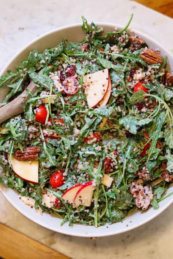 apple pecan salad in a mixing bowl with dressing.