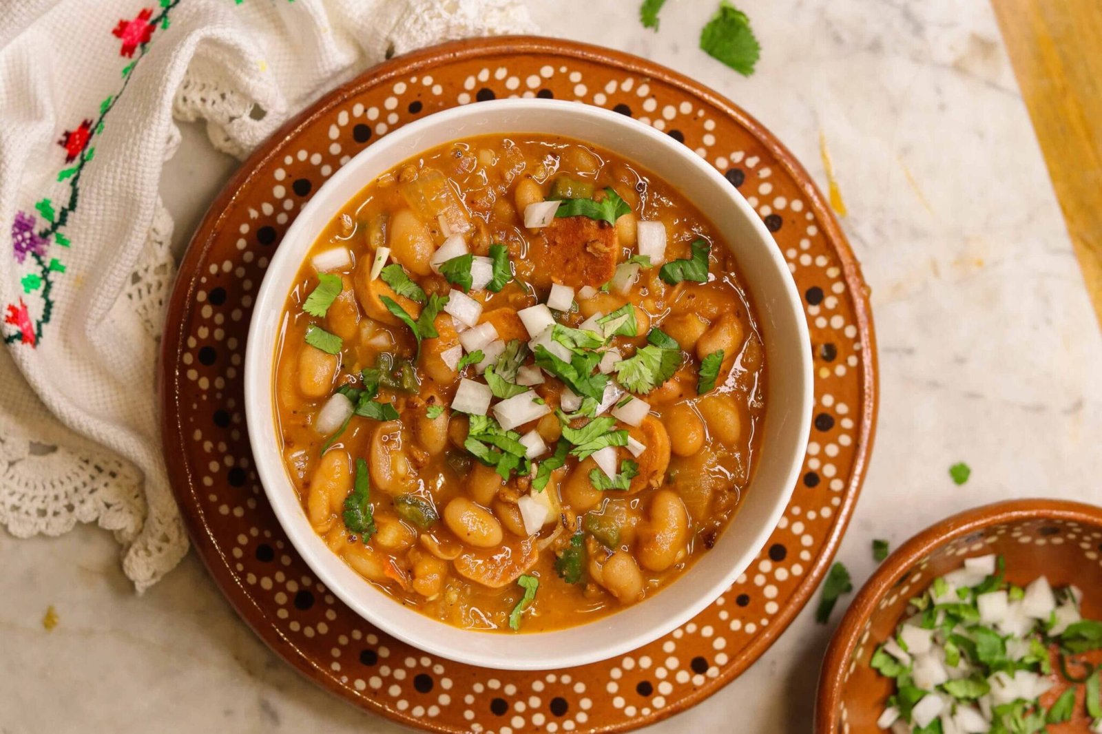 charro beans in a white bowl with cilantro and onions on top.