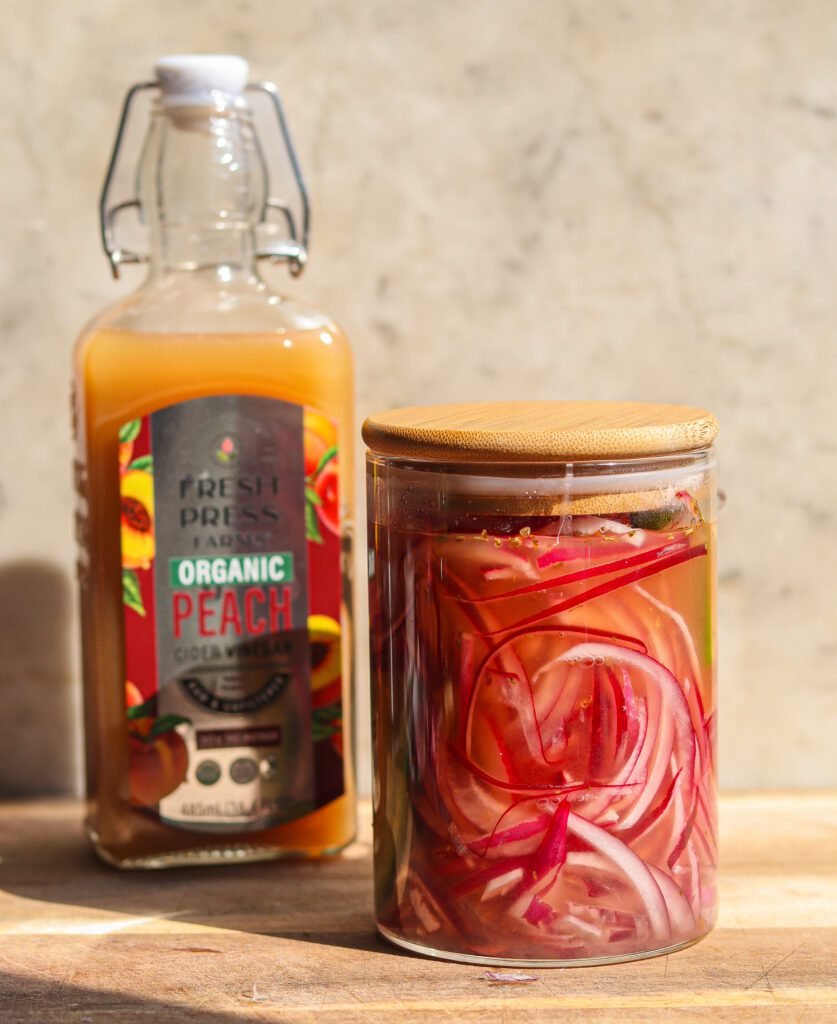 mexican pickled onions in a jar with peach cider vinegar.